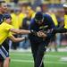 XX and Cato June reach for the ball carried by Jerry Diorio during the Victors Classic alumni football game at Michigan Stadium on Saturday. Melanie Maxwell I AnnArbor.com